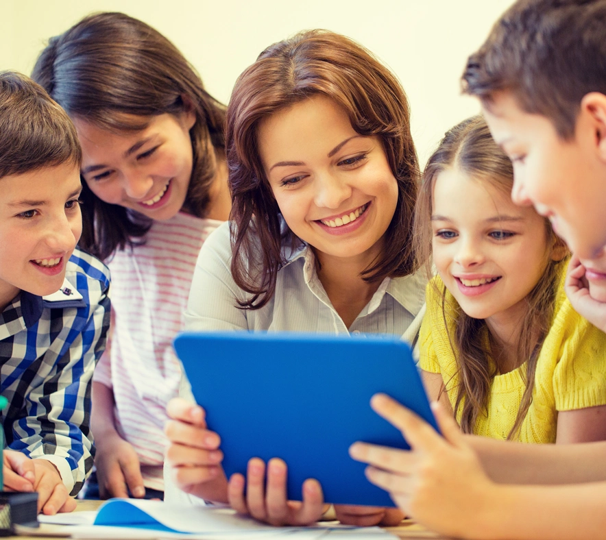 teacher surrounded by her students all reading from a tablet together